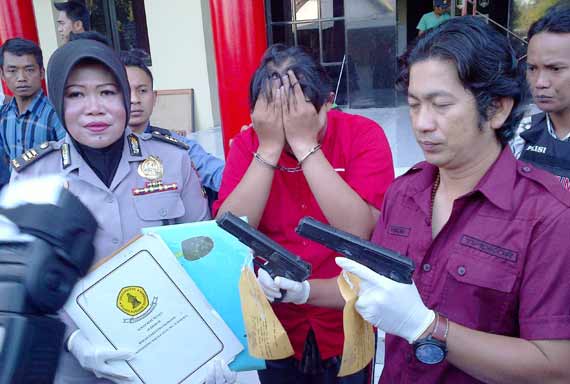 Kasat Reskrim menujukan senpi mainan dan Andika yang menutupi wajahnya. foto: rusmiyanto/BANGSAONLINE