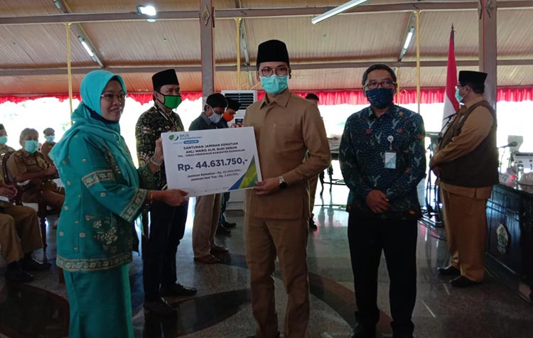 Bupati R. Abdul Latif Amin Imron bersama Deputi Direktur BPJS Ketenagakerjaan Kantor Wilayah Jatim, Dodo Suharto berikan santunan jaminan kematian kepada salah satu perwakilan guru ngaji dan madin di Pendopo Agung Bangkalan, Senin (15/6/2020).
