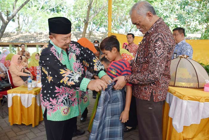 Mbah Tarom saat memasangkan sarung kepada salah satu peserta khitanan massal.