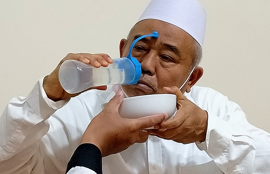 Prof. Dr. KH. Asep Saifuddin Chalim saat memperagakan memasukkan garam krosok yang dilarutkan dalam air mineral ke dalam hidung dan mulut untuk merontokkan virus corona di sela salat malam dan istighatsah di Pondok Pesantren Amanatul Ummah Surabaya, Kamis (22/7/2021). foto: mma/ bangsaonline.com