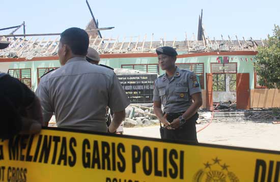 Petugas memasang police line di lokasi kebakaran untuk keperluan penyidikan. foto: suwandi/BANGSAONLINE