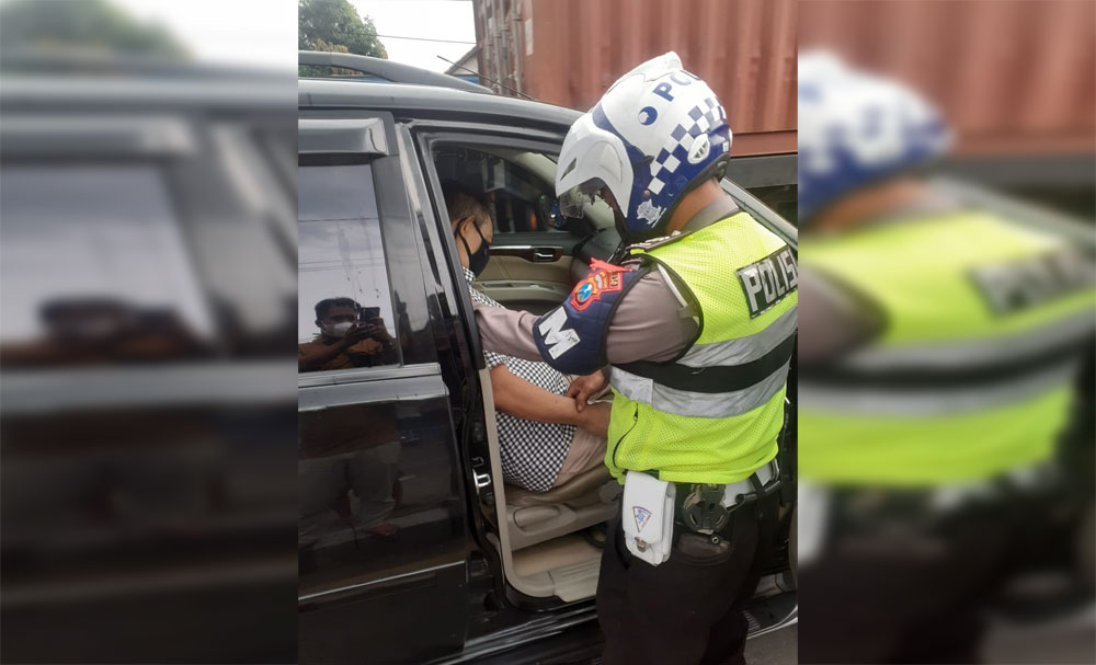 Petugas kepolisian saat mengevakuasi seorang pria yang meninggal dalam mobil akibat serangan jantung di Jalan Raya Geluran, Sidoarjo.