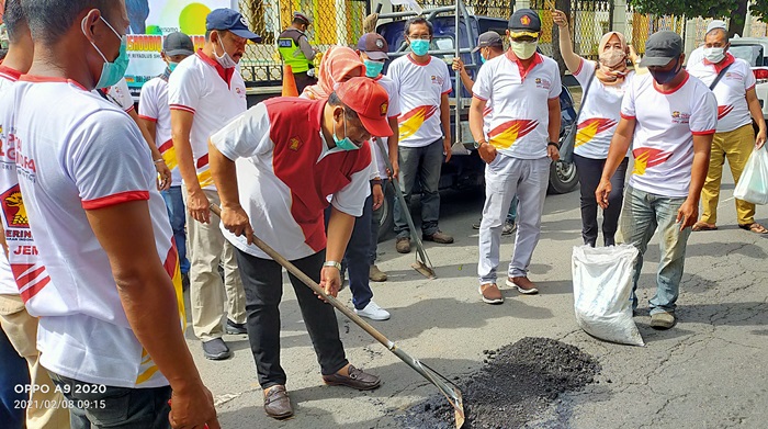 Para kader DPC Partai Gerindra Jember bahu membahu menambal jalan berlubang pakai aspal.