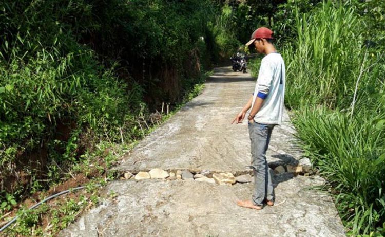 Warga Dusun Badut, Desa Jugo, Kecamatan Mojo saat menunjukkan tanah retak yang terjadi di daerahnya. (foto: MUJI/ BANGSAONLINE)