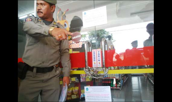 SEGEL: Petugas Satpol PP menyegel dan menutup paksa Alfamart yang tidak kantongi ijin. foto: haris/BANGSAONLINE