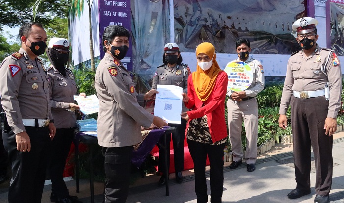 Kasatlantas Polres Blitar I Putu Angga Feriyana saat menyerahkan sertifikat vaksin kepada salah satu pengendara.
