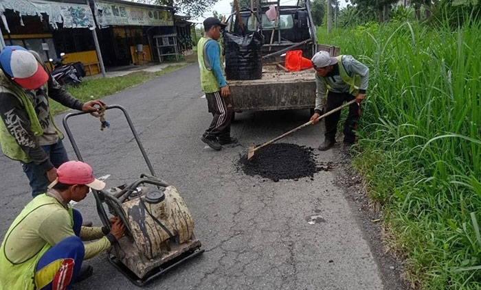 Petugas dari Dinas PUPR Jombang saat memperbaiki jalan.