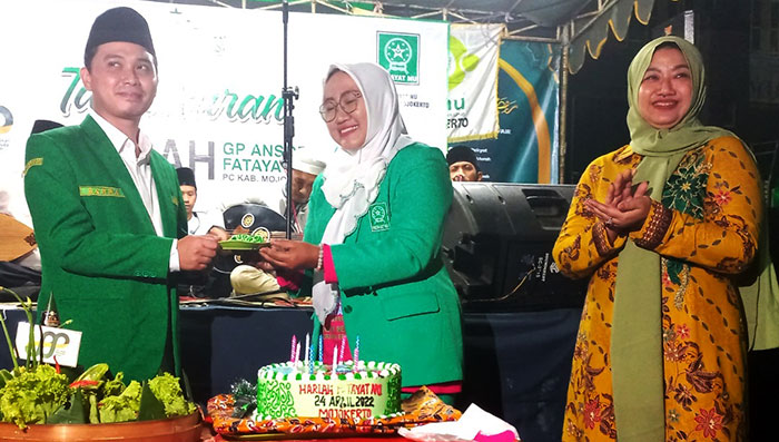 Ketua GP Ansor Kabupaten Mojokerto, Gus Barra, saat menyerahkan potongan tumpeng kepada Ketua Fatayat NU didampingi Ketua DPRD Kabupaten Mojokerto, Ayni Zuroh.