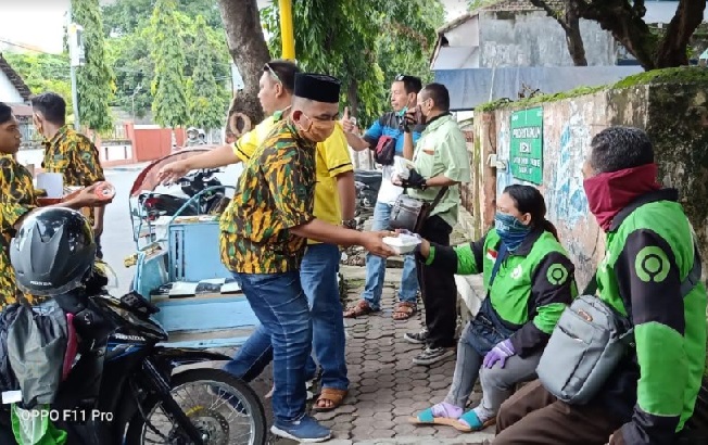 Jajaran DPD Golkar, Fraksi Golkar, dan AMPI membagikan nasi bungkus dan masker kepada para ojol. Berharap meringankan beban hidup akibat Covid 19. foto: YUDI EP/ BANGSAONLINE