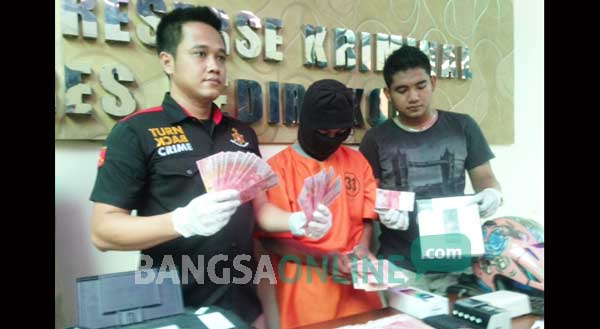 Tersangka bersama barang bukti uang palsu yang tersisa dan beberapa handphone hasil kejahatan saat digelar di Mapolres Kediri Kota. foto: arif kurniawan/ BANGSAONLINE