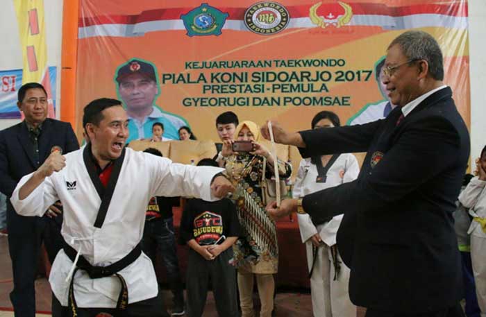 SATU PUKULAN: Ketua Umum KONI Sidoarjo M Franki Efendi memukul papan hingga pecah usai menerima sabuk hitam Taekwondo, Minggu (17/12) sore. foto: ist
