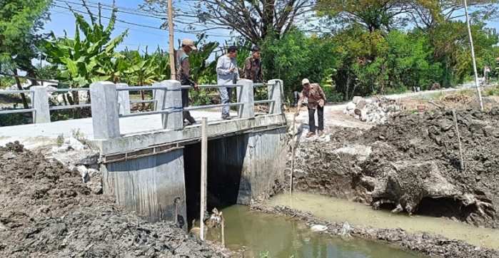 Kades Sekargadung Sumarto bersama tim pelaksana saat meninjau dam pintu air. Foto: Ist
