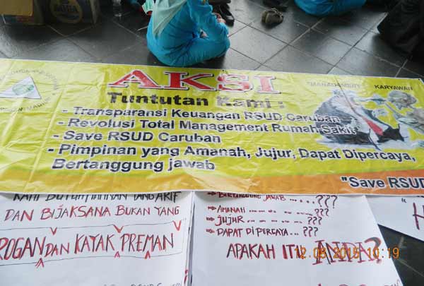 BEBER POSTER – Sejumlah poster berisi kecaman yang dibawa pegawai RSUD Caruban Madiun saat berunjuk rasa ke DPRD Madiun, Rabu (12/8). Foto: zainal abidin/BANGSAONLINE