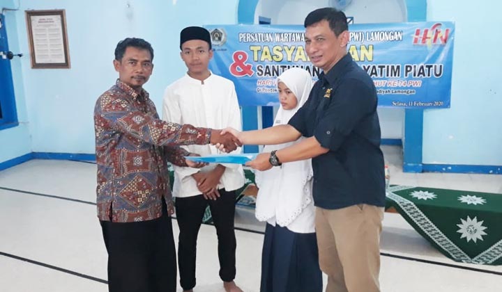 Ketua PWI Lamongan Bachtiar Febriyanto saat menyerahkan santunan dan foto bersama.
