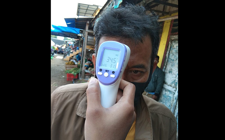 Salah satu pengunjung pasar saat sedang diukur suhu tubuhnya.
