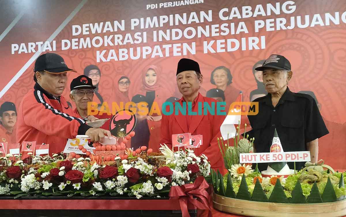 Ketua DPC PDIP Kabupaten Kediri, Murdi Hantoro, saat memotong tumpeng yang selanjutnya diberikan kepada kader senior. Foto: MUJI HARJITA/BANGSAONLINE