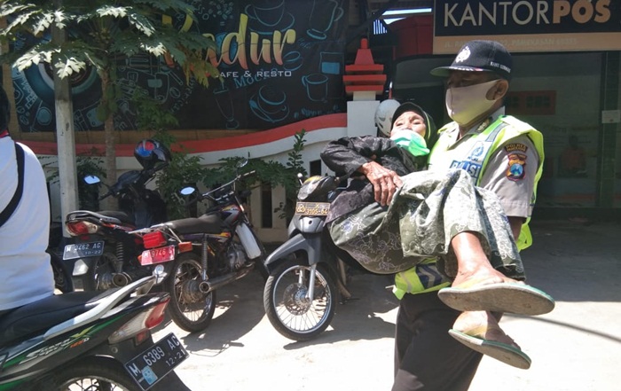 Aiptu Gatot Irianto saat menggendong nenek yang mau mengambil BST di kantor pos