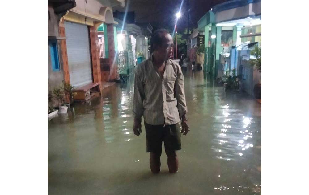 Warga Desa Banyutami menerobos jalan desa yang terendam banjir rob. Foto: Ist.