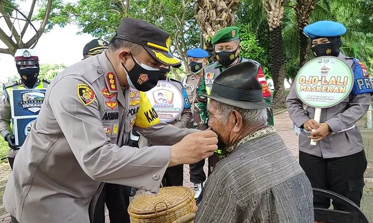 Kapolresta Banyuwangi Kombes Pol. Arman Asmara Syarifuddin sedang memakaikan masker. (foto: ist)