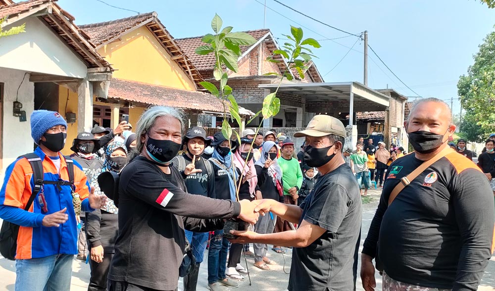Koordinator EPPI, Benny Prasetya, saat menyerahkan secara simbolis bantuan bibit alpukat kepada Kepala Desa Senden, Mat Jumain, sebelum aksi bersih-bersih sampah di sungai. Foto: MUJI HARJITA/BANGSAONLINE