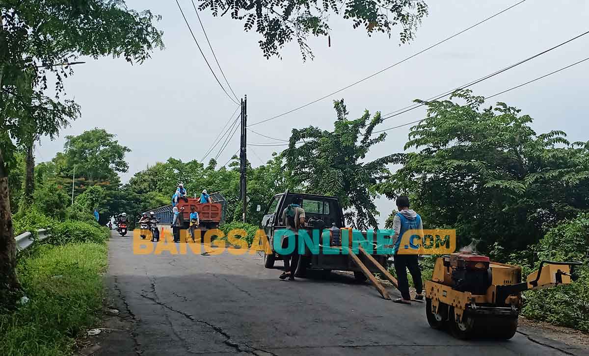 Petugas URC DPUTR Gresik saat tambal sulam kerusakan jalan di samping jembatan tol penghubung Desa Kembangan dengan Desa Kedanyang. Foto: SYUHUD/BANGSAONLINE