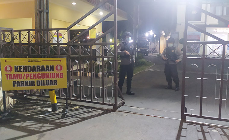 Personel bersenjata dan alat pelindung lengkap berjaga di gerbang masuk Polresta Banyuwangi.