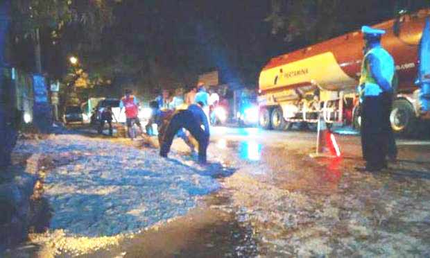 BIKIN MASALAH: Petugas Polsek Mojosari mengawasi warga membersihkan tumpahan limbah bubur kertas di jalan raya. foto: gunadhi/BANGSAONLINE