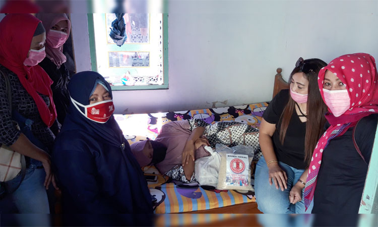 Koordinator Relawan Gotong Royong Kediri, Irma Yulianti, saat menyerahkan bantuan secara simbolis kepada Ketua PDKK, Umi Salamah yang menerima dengan rebahan. foto: MUJI HARJITA/ BANGSAONLINE