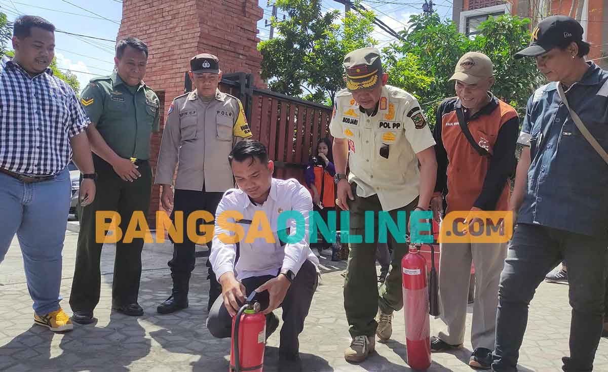 Lurah Gunung Gedangan, Andika (kemeja putih), dan Kepala Satpol PP Kota Mojokerto, Modjari,  saat memadamkan kobaran api dalam simulasi penanganan kebakaran. Foto: YUDI EKO PURNOMO/BANGSAONLINE
