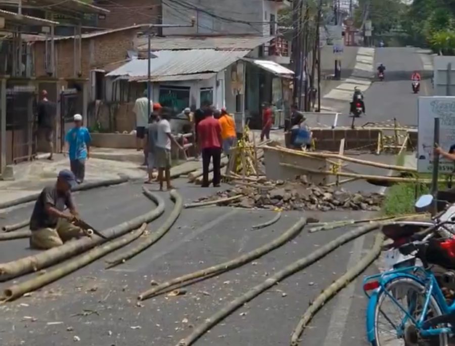 Warga kelurahan Pandanwangi, Blimbing saat memperbaiki jembatan dengan alat dan material seadanya