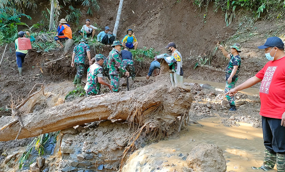 Petugas gabungan dari personel BPBD, Perangkat Desa Blimbing, Koramil, dan Polsek Mojo saat melakukan pembersihan di lokasi jembatan Dusun Semoyo yang terputus. foto: MUJI HARJITA/ BANGSAONLINE