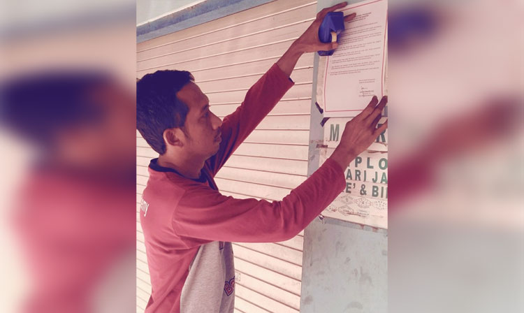Salah satu warga menempelkan selebaran dari Kadinkes Bangkalan terkait SOP isolasi mandiri guna Pencegahan Covid-19, Ahad (5/4).
