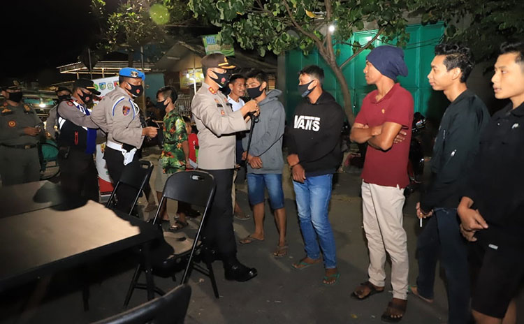 Kapolres Kediri, AKBP Lukman Cahyono saat memakaikan masker kepada warga yang terjaring operasi yustisi. (foto: ist).