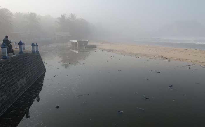 Wisatawan saat melihat gelombang pasang dari pelabuhan perikanan pantai.