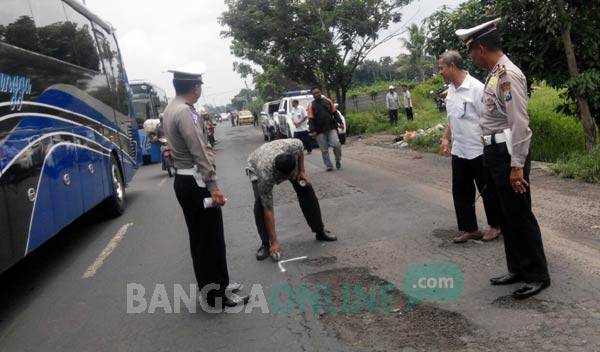 TAK KUNJUNG DITAMBAL: Pemeberian tanda di lubang Jalur Nasional Rute 15 oleh Satlantas Polres Jombang. foto: rony suhartomo/ BANGSAONLINE