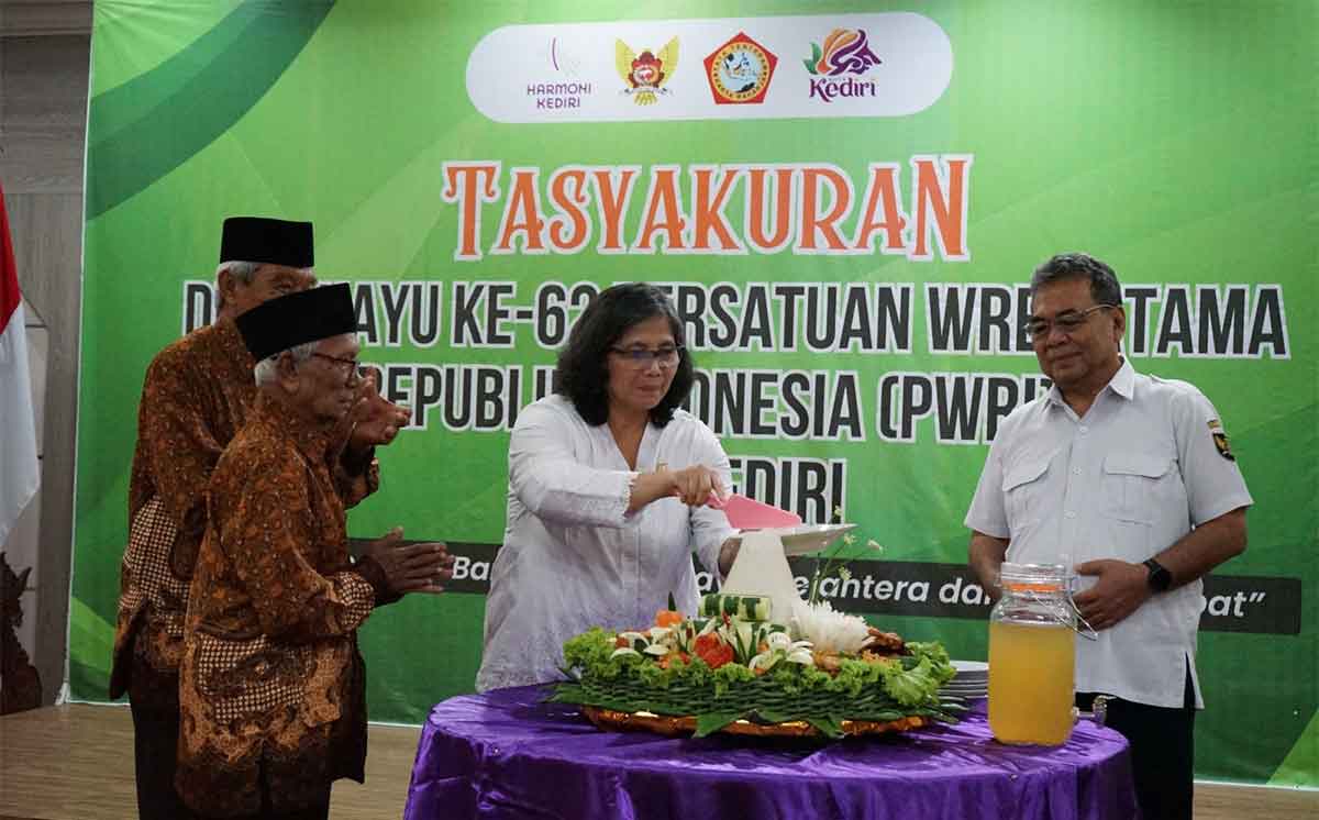 Pj Wali Kota Kediri, Zanariah, saat memotong tumpeng dan diberikan kepada anggota PWRI tertua. Foto: Ist