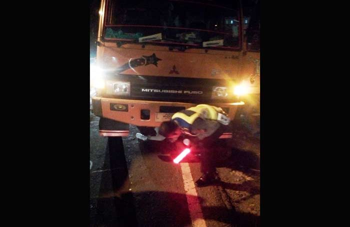 Petugas saat memeriksa kondisi truk yang menyambar seorang ibu.